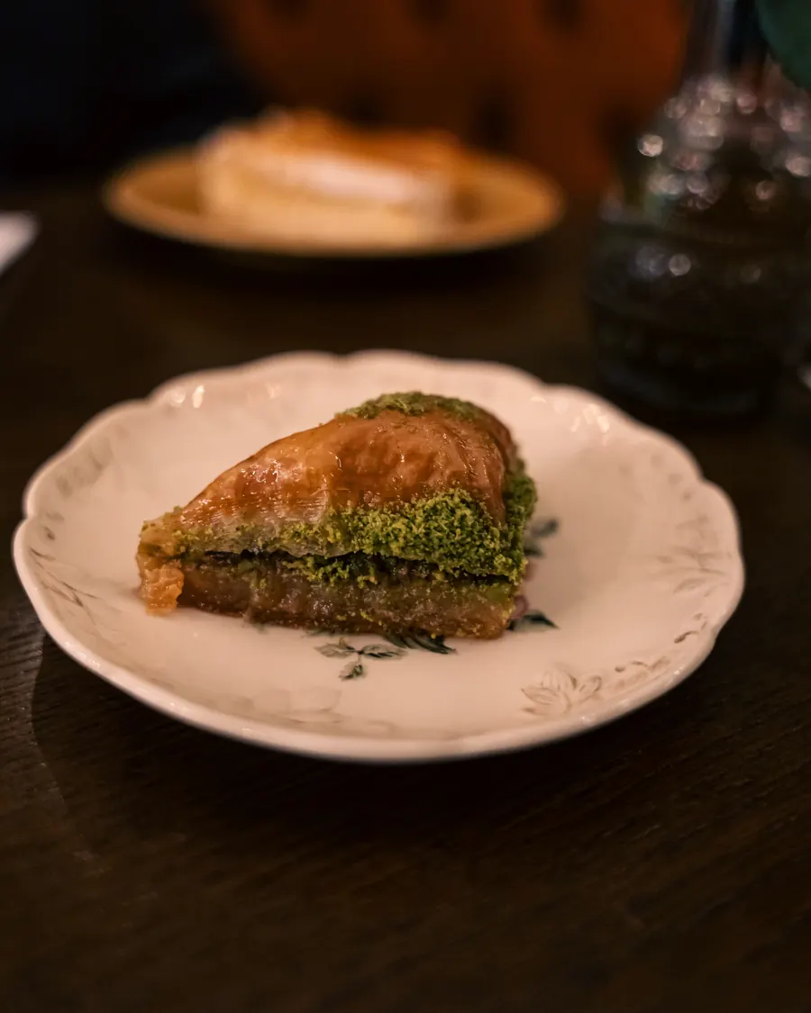 A slice of pistachio baklava on a vintage plate