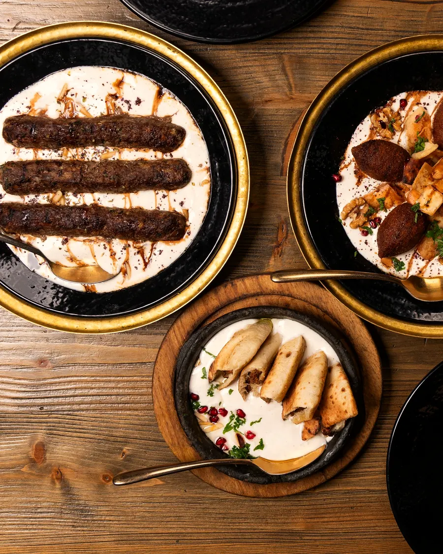 Lamb kofta and kibbeh in warm yoghurt on black-and-gold plates