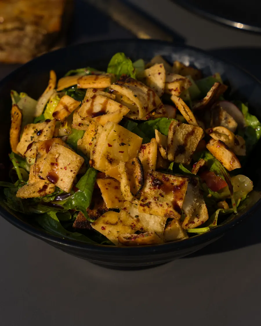 Fattoush salad with crisp bread and greens in a dark bowl