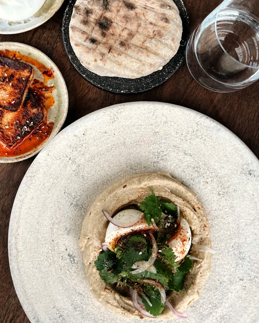 Hummus topped with herbs and red onion, with grilled flatbread and labneh